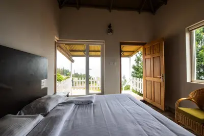 a bedroom with a large bed and a large window at Tranqville Resorts in Ooty