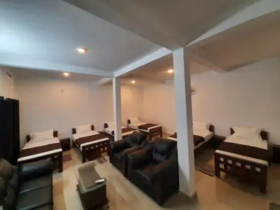 a room with two beds and a couch and chairs at 3 Hills Hostel in Wayanad