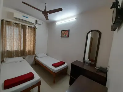 a bedroom with two beds and a mirror and a dresser at SUPREME RESIDENCY in Coimbatore
