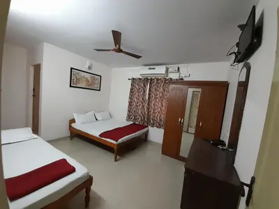 a room with two beds and a flat screen tv at SUPREME RESIDENCY in Coimbatore
