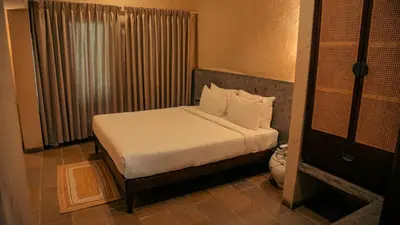 a bedroom with a bed with white sheets and pillows at Fireflies Kabini in Begūr