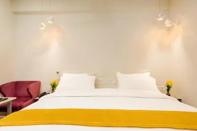 a bedroom with a white bed and a red chair at Hotel Vijay Fablis in Coimbatore