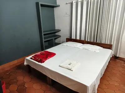 a bedroom with a bed with white sheets and red pillows at H Villa in Nilambūr