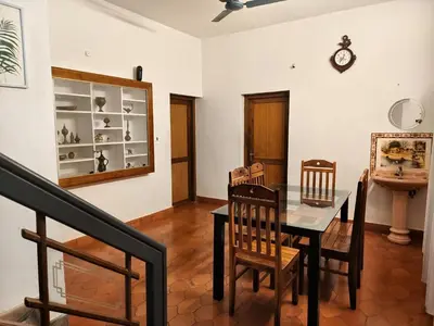 a dining room with a table and chairs and a clock at H Villa in Nilambūr