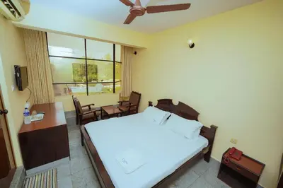 a bedroom with a bed and a table and a window at Hotel oneiro in Trichūr