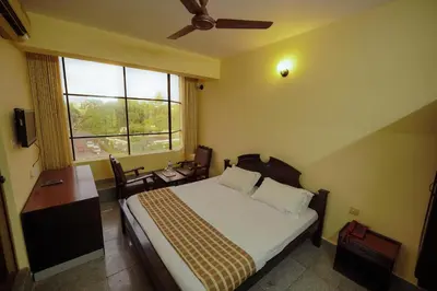 a bedroom with a bed and a desk and a window at Hotel oneiro in Trichūr