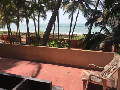 a white chair sitting on a balcony looking at the beach at Kizhunna rock beach house in Kannur