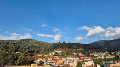 a town on a hill with houses and trees at Karpagam Residency in Ooty