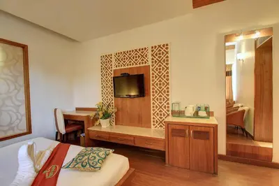 a bedroom with a bed and a desk and a television at Hotel Prince Gardens in Coimbatore
