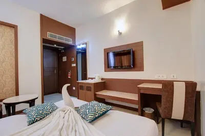 a room with a bed and a desk and a tv at Hotel Prince Gardens in Coimbatore