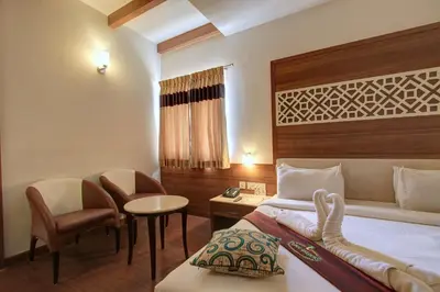a hotel room with a bed and a desk and chair at Hotel Prince Gardens in Coimbatore
