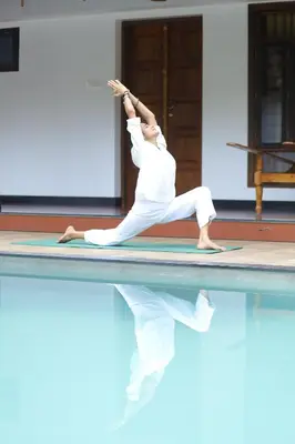 a woman doing yoga on the edge of a swimming pool at Vajra Ayurveda and Yoga Retreat in Cochin