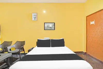 a bedroom with a bed with yellow walls and chairs at Super Collection O Coorg in Madikeri