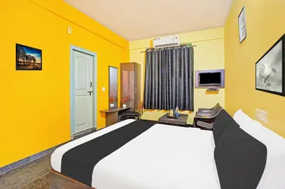a bedroom with a large bed with yellow walls at Super Collection O Coorg in Madikeri