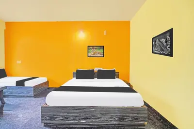 two beds in a room with an orange wall at Super Collection O Coorg in Madikeri