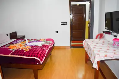 a room with a bed and a table and a tv at AC MIST in Munnar