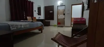 a bedroom with a bed and a chair in it at Pauls Retreat Wayanad , Family Resort in Wayanad