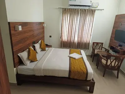 a bedroom with a bed and a desk and a chair at PPH Living Athithi Inn Corporate Stay in Coimbatore