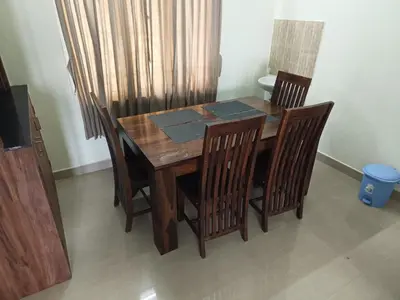 a dining room table with chairs and a wooden table at PPH Living Athithi Inn Corporate Stay in Coimbatore