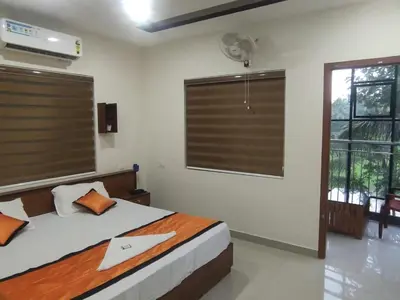 a bedroom with a bed and a window with a fan at PMS Dhabi Residency in Kottakkal