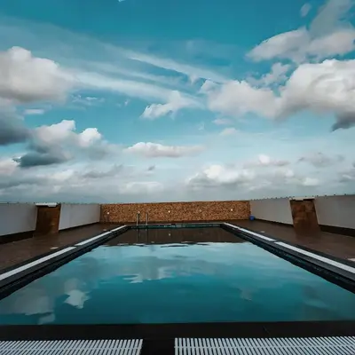 a swimming pool with a cloudy sky in the background at GDC - Apartment suites in Ernakulam