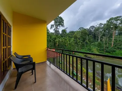 a balcony with a view of a river and trees at The Hosteller Coorg Rainforest, Madikeri in Madikeri