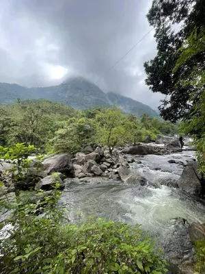 a river with a mountain in the background at Casa Riverdale Farm Stay in Vallikavungal