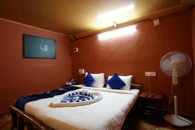 a bedroom with a bed with blue pillows and a fan at Misty Morning Resorts Wayanad in Ambalavayal