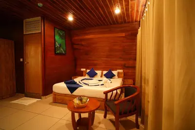 a bedroom with a bed and a table and a chair at Misty Morning Resorts Wayanad in Ambalavayal