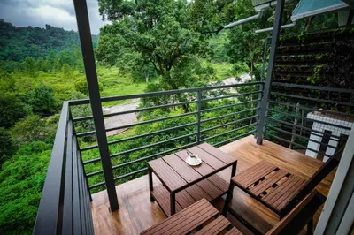 a balcony with a wooden table and chairs on it at Misty Range Resorts , Marayoor in Marayoor