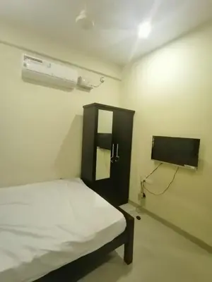a small room with a bed and a tv at Queens Residency in Trichūr