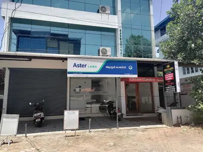 a store front of a building with a motorcycle parked outside at Green Garden Apartments in Kodungallūr