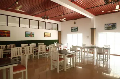 a dining room with white tables and white chairs at NIRVANA HOLISTIC LIVING in Varagampadi