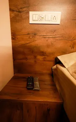 two remote controls sitting on a wooden table next to a bed at Chakalakkal Residency in Sultan Bathery