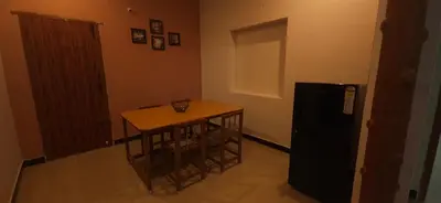 a small kitchen with a small table and a refrigerator at SHI's Triveni Spacious 2BHK Villa in Pappampatti, Coimbatore in Coimbatore