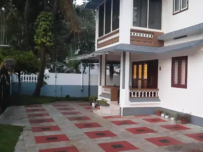 a white house with a courtyard in front of it at NEST Mdy in Mananthavady