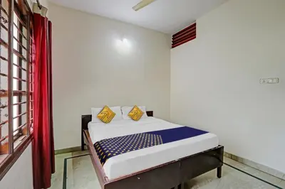 a bedroom with a bed with blue and yellow pillows at Hotel O Vishu Moni Residency in Mysore