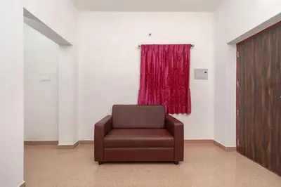 a brown chair in a room with a red curtain at Varun residency in Coimbatore