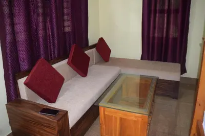 a couch with two pillows and a glass table at Golden Peak Estate Homestay in Wayanad