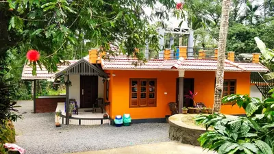 a small orange house in the middle of a garden at Golden Peak Estate Homestay in Wayanad