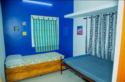 a blue bedroom with a bed and a window at SHI's Bhairavi Peaceful 2bhk villa - - On the way 2 isha-Adiyogi , Maruthamalai in Coimbatore