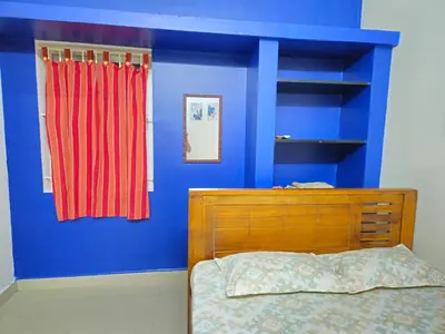 a blue bedroom with a bed and a red curtain at SHI's Bhairavi Peaceful 2bhk villa - - On the way 2 isha-Adiyogi , Maruthamalai in Coimbatore