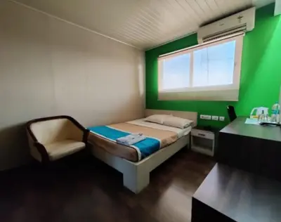 a bedroom with a bed and a green wall at Hotel Mothimahal in Trichūr