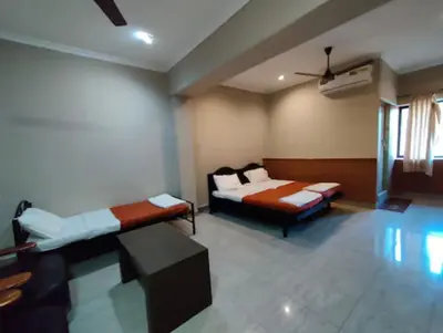 a room with two beds and a ceiling fan at Hotel Mothimahal in Trichūr