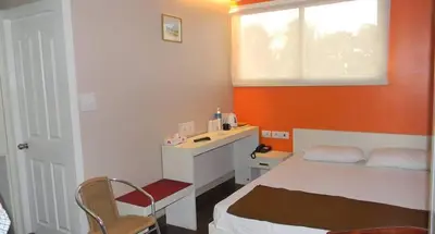a small room with a bed and a desk at Hotel Mothimahal in Trichūr