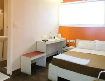 a hotel room with a bed and a desk and a bed at Hotel Mothimahal in Trichūr