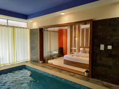 a bedroom with a swimming pool and a bed and a tub at Karapuzha Village Resort in Wayanad