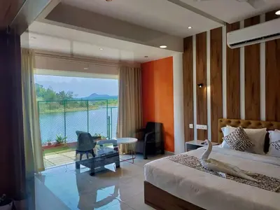 a bedroom with a bed and a view of the water at Karapuzha Village Resort in Wayanad