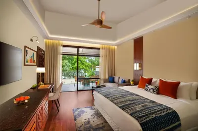 a bedroom with a large bed and a living room at Taj Wayanad Resort & Spa, Kerala in Wayanad