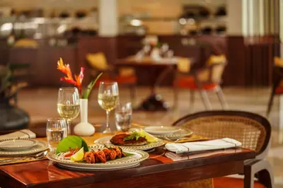 a table with plates of food and glasses of wine at Taj Wayanad Resort & Spa, Kerala in Wayanad